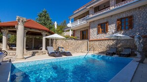 A pool area with lounge chairs, a stone building with a balcony, and a statue. - Unique flat with magnificent sea views, pool, BBQ and only 700 metres to the beach (Crikvenica)