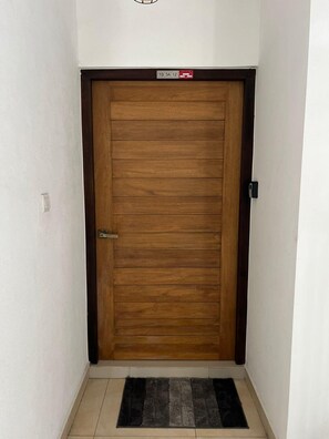 A wooden door with a metal handle and a small sign above it.