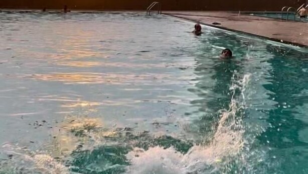 Una piscina con el horizonte de la ciudad al fondo durante el atardecer.