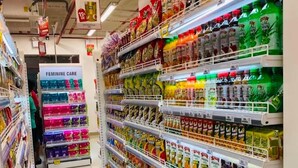 Un pasillo de supermercado con varios productos en las estanterías, incluyendo bebidas y artículos de cuidado personal.