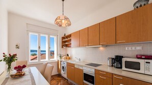 Una cocina moderna con armarios de madera, horno empotrado, microondas y pileta.