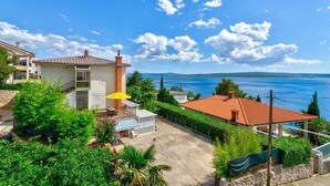 A coastal property with a terrace, a small building with a chimney, and a view of the sea. - Fantastic flat only 150 metres to the beach with sea view, sun lounger, barbecue, dog-friendly (Dramalj)