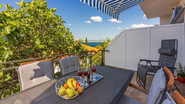 An outdoor patio with a table set for two, a chair, and a view of the sea. - Fantastic flat only 150 metres to the beach with sea view, sun lounger, barbecue, dog-friendly (Dramalj)