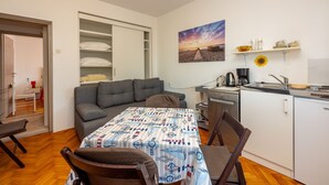 A compact living space with a sofa, a dining table, a kitchenette, and a wardrobe. - Fantastic flat only 150 metres to the beach with sea view, sun lounger, barbecue, dog-friendly (Dramalj)