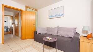 Ein modernes Wohnzimmer mit einem grauen Sofa, gestreiften Kissen, einem kleinen runden Tisch mit Tablett und einer Lampe auf einem Holznachttisch.