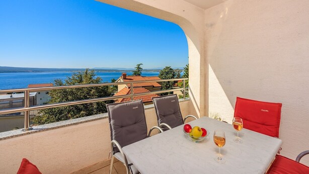 Ein Balkon mit Tisch, Stühlen und Meerblick.