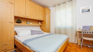 Ein Schlafzimmer mit Bett, Holzschrank und Schreibtisch mit Stuhl.