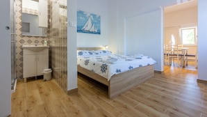 Ein Schlafzimmer mit einem hölzernen Bett, einem weißen Waschbecken und einem Badezimmer mit gemusterten Fliesen.