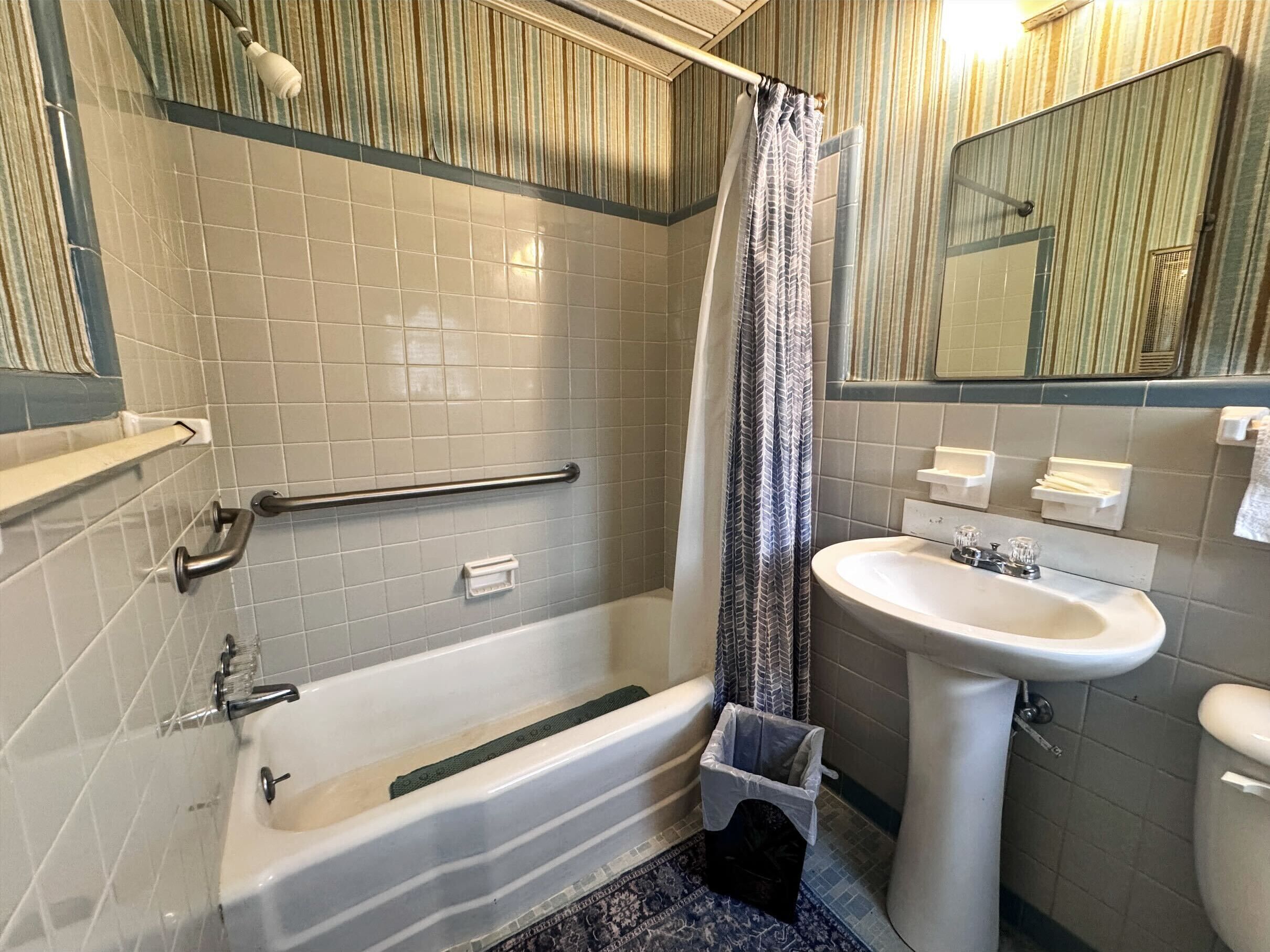 Un baño con bañera, ducha con cortina, lavabo e inodoro.