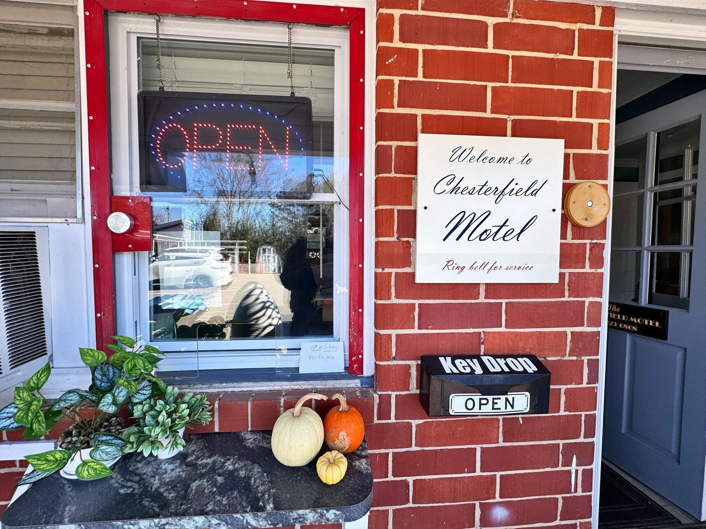 A brick building with a sign reading "Welcome to Chesterfield Motel" and a "Ring bell for service" sign.