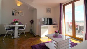 A modern living room with a dining area, a TV, and a balcony with outdoor seating. - Charming top floor apartment with sea view and view of the old town of Porec (Porec)