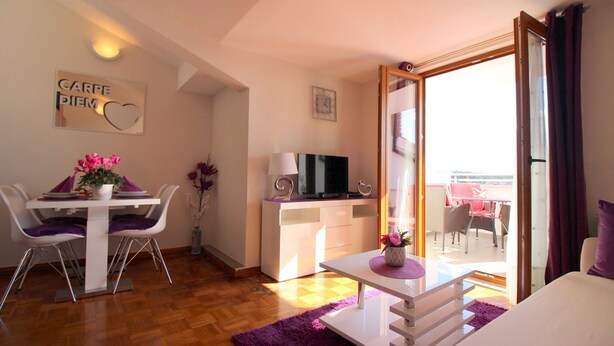 A modern living room with a dining area, a TV, and a balcony with a view. - Charming top floor apartment with sea view and view of the old town of Porec (Porec)