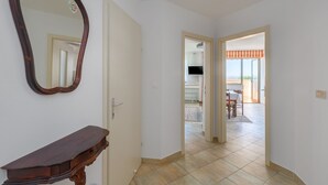 A hallway with a wooden console table and a mirror, leading to a balcony with a view. - Idyllic flat just 250 metres from the beach with pool, sea view, barbecue area, loungers (Porec)