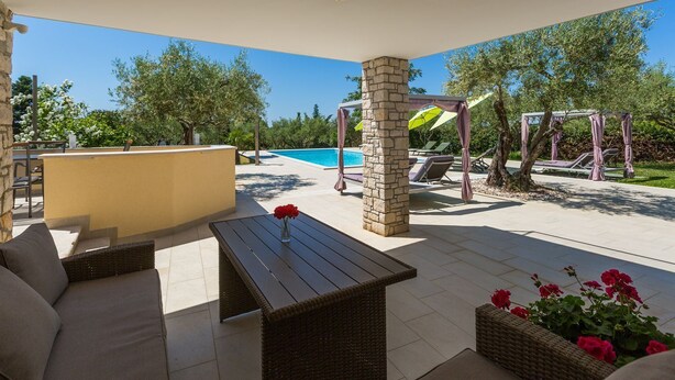 An outdoor patio area with a pool, lounge chairs, and a table with a vase of flowers. - Idyllic flat just 250 metres from the beach with pool, sea view, barbecue area, loungers (Porec)