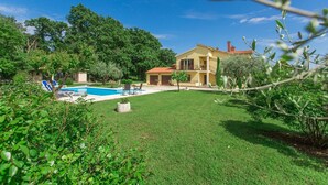A two-story house with a swimming pool, surrounded by lush greenery and trees. - Dog-friendly paradise with pool, playground, barbecue area, private terrace (Sveti Lovrec)