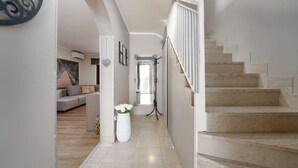 A modern interior with a staircase, a hallway leading to a living area, and a decorative wall piece. - Exquisite holiday home with private garden, sun loungers, high chair, washing machine - only 700 metres to the beach (Porec)