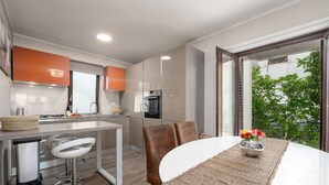A modern kitchen with a dining area, featuring a large window with a view of greenery. - Exquisite holiday home with private garden, sun loungers, high chair, washing machine - only 700 metres to the beach (Porec)