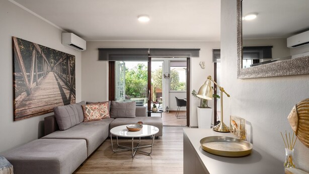 A modern living room with a grey sectional sofa, a round coffee table, and a large painting of a bridge. - Exquisite holiday home with private garden, sun loungers, high chair, washing machine - only 700 metres to the beach (Porec)
