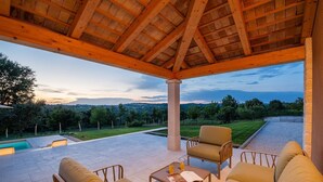 A covered outdoor seating area with a pool, chairs, and a view of the landscape. - Impressive villa with panoramic views, private pool, table tennis, table football, playground, baby cot (Pazin)