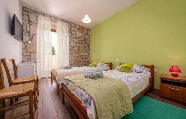A bedroom with two beds, a stone wall, a television, and a desk with a lamp. - Mediterranean and dog-friendly finca with private pool, barbecue area, washing machine, WiFi (Porec)