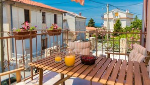 A wooden table with drinks and a bowl of fruit on a balcony with metal railings and potted plants. - Charming flat just 300 metres from the beach with sea views, washing machine, WiFi (Crikvenica)