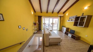 Un salón con sofá, televisión y piso de madera.