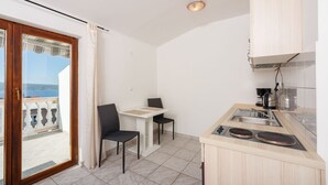 A compact kitchen with a dining area, a view of the sea, and a balcony with a wooden railing. - Idyllic studio flat with magnificent sea views, private car park, WiFi (Crikvenica)
