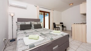 A bedroom with a bed, bedside table, and a small kitchenette. - Idyllic studio flat with magnificent sea views, private car park, WiFi (Crikvenica)