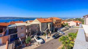 A coastal residential area with terracotta-roofed buildings, a parking area, and a clear view of the sea. - Idyllic studio flat with magnificent sea views, private car park, WiFi (Crikvenica)