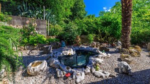 A garden with a hot tub surrounded by rocks and plants. - Charming flat just 600 metres from the beach with sea views, charcoal grill, WiFi (Dramalj)