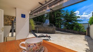 Ein Zimmer mit einem Holztisch, einer bunten Tasse und Blick auf einen Garten und ein Tor.
