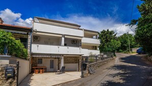 Ein zweistöckiges Gebäude mit Balkon, überdachter Außenlounge und einer Steinsäule.