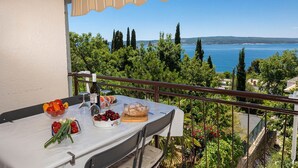 Un balcón con mesa lista para una comida, con vistas panorámicas a un lago y colinas.
