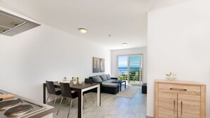 A modern apartment with a dining area, a sofa, and a view of the outdoors. - Modern flat only 90 metres to the beach with sea view, underground car park, air conditioning (Crikvenica)