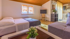 Une chambre avec deux lits, une télévision, un coin cuisine et un plafond en bois.