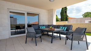 A patio with a table and chairs, a sliding glass door, and a view of the surrounding area.