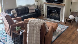 A living room with a fireplace, a sofa, a coffee table, and a television.