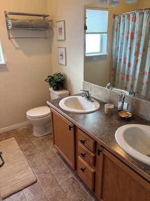 A bathroom with a toilet, sink, vanity, and a shower curtain. - Charming 3-bedroom house with Hot Tub in Donnelly (Donnelly)