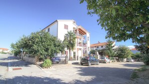 A two-story building with a white facade, a balcony, and a gated entrance. - Charming studio flat with Mediterranean garden, barbecue, sun lounger, WiFi (Novigrad)