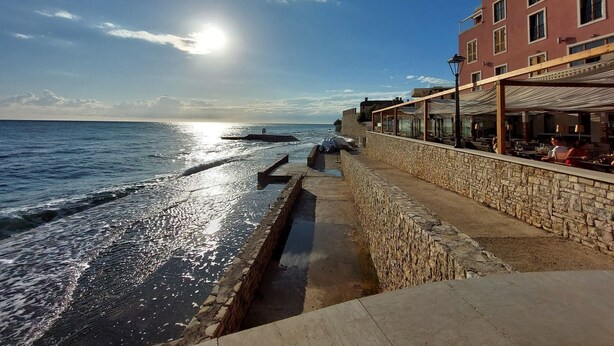 A coastal view with a stone wall and a building with outdoor seating overlooking the sea. - Charming studio flat with Mediterranean garden, barbecue, sun lounger, WiFi (Novigrad)