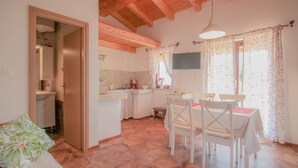 A cozy room with a bed, a small table, and chairs. There's a kitchenette with a sink and a stove. - Charming studio flat with Mediterranean garden, barbecue, sun lounger, WiFi (Novigrad)