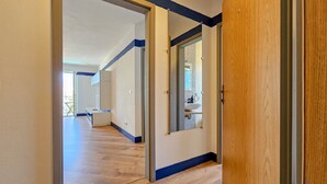 A hallway with wooden flooring, a white wall, and a door leading to a bathroom with a mirror and sink. - Idyllic flat with sea view, pool, barbecue, washing machine, private car park (Novigrad)