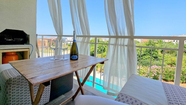 A balcony with a table, a bottle of wine, and a grill. - Idyllic flat with sea view, pool, barbecue, washing machine, private car park (Novigrad)