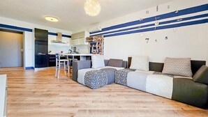 A modern living room with a sofa, a dining area with a table and chairs, and a kitchen in the background. - Idyllic flat with sea view, pool, barbecue, washing machine, private car park (Novigrad)