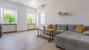 A modern living room with a grey sofa, wooden coffee table, and a hanging light fixture.