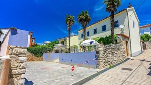 A gated residential area with stone walls, a clear blue sky, and palm trees.