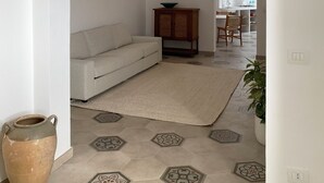 A living room with a sofa, a wooden cabinet, a hanging light fixture, and a patterned floor.