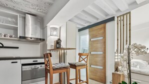 Eine moderne Küche mit weißen Schränken, einer Edelstahl-Dunstabzugshaube und einem Holztisch mit zwei Stühlen.