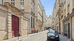 Eine schmale Straße gesäumt von historischen Gebäuden, eine rote Tür und ein geparktes Auto.