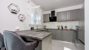 Una cocina moderna con una isla central, armarios grises e iluminación colgante.